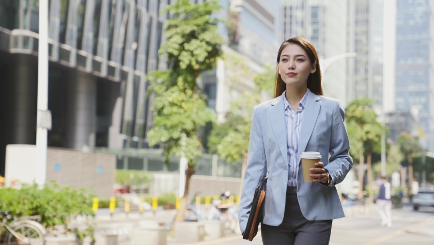 Successful young asian woman walking in central business district  in modern city | Shutterstock HD Video #1068615752