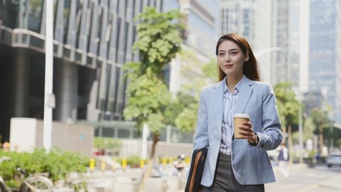 successful young asian woman walking in central business district  in modern city