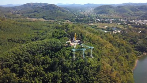 Chiang Khan Skywalk. Tall Walking Buddha Statue And Glass Skywalk By The Mekong River At Chiang Khan District In Loei, Thailand. aerial drone orbit