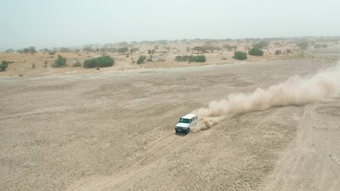 Traveling by jeep in African deserts and a cloud of dust from behind