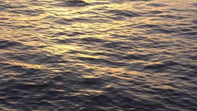 Relaxing ocean video in 4k resolution. Dark water surface with small waves pattern and copy space. Golden sun reflecting on moving sea. Blue natural background. Tranquility and peace. Meditation.