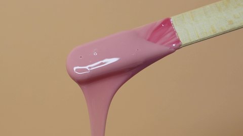 Depilatory wax master mixes heating wax with a wooden spatula. Removing unwanted hair with wax. Woman beauty