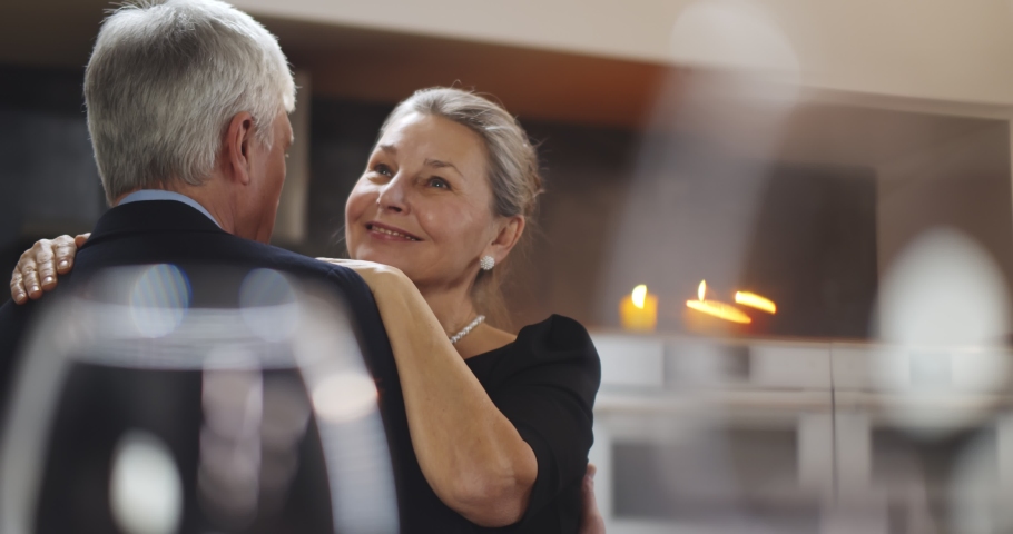 Aged caucasian couple enjoying time at home together dancing in kitchen and smiling. Portrait of happy senior husband and wife dancing having romantic dinner at home Royalty-Free Stock Footage #1068639791