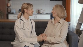 Young woman doctor talking with sick old woman. They are posing, looking at the camera. Old people home care concept.Slow motion video.