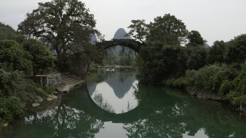 Drone shot of arch bridge over beautiful river against sky - Yangshuo, China