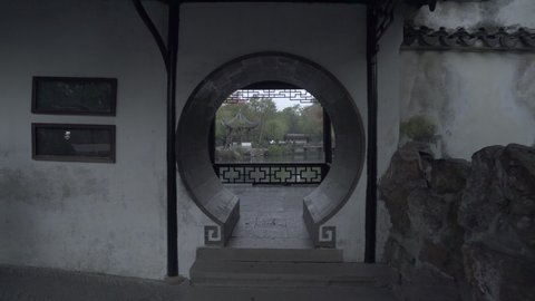 Archway in structure by pond against trees with people exploring at park - Suzhou, China