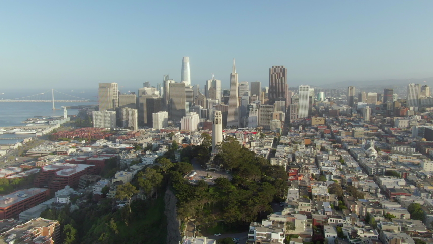 Aerial approach of the soaring downtown skyline with a tilt down to quaint, cozy, and historic Telegraph Hill and Coit Tower - San Francisco, California Royalty-Free Stock Footage #1068647288