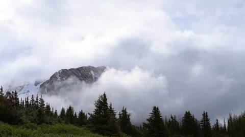 Lockdown time lapse shot of clouds covering mountain peak against sky - Banff, Canada