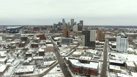 Aerial shot of vehicles on street in city with snow and canal, drone flying forward over buildings against sky - Minneapolis, Minnesota