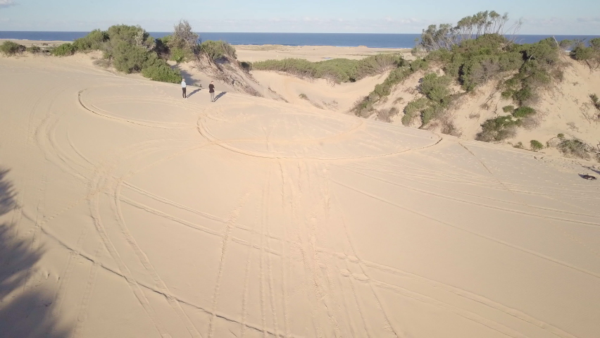 Aerial Ascend: Friends On Sand Dune Near Sea During Sunny Day