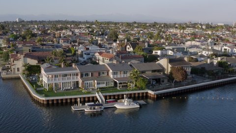 Aerial Pan: Peaceful Harbor With Docked Boats Abutting Large Neighborhood Stretching Into Distance