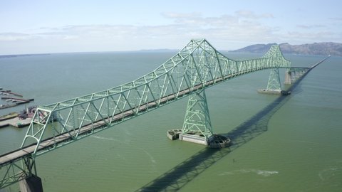 Aerial Forward: Towering Green Metal Truss Bridge Over Wide River In Sunshine