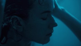 4k Close-up shot in a low key. dark neon blue light, Young woman takes a shower. Hair wash care for long curly hair. Wet hair on the face of a beautiful girl.  - Powered by Shutterstock - Get 15% off with code: PIKWIZARD15