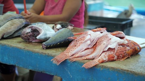 Pan: Flies Buzz Around Piles Of Fish Displayed At Fishmongers Stall While Vendors Wave Fly Swatters