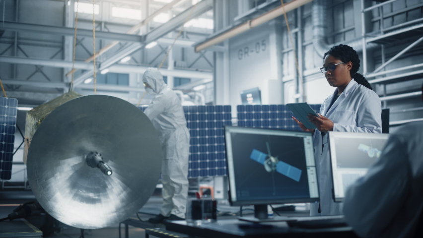 Female Engineer Uses Tablet Computer while Working on Satellite Construction. Aerospace Agency Manufacturing Facility: Scientists Build, Assemble Spacecraft for Space Exploration, Observation Mission | Shutterstock HD Video #1068654092