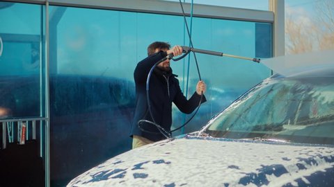 Man Washing Car On Wash Self-Service.Washes Automobile with Foam And Osmosis Water.Before Detailing And Waxing Vehicle.Dirty Car Cleaning And Protection With Active Foam.Clean Water Spray Pressure.