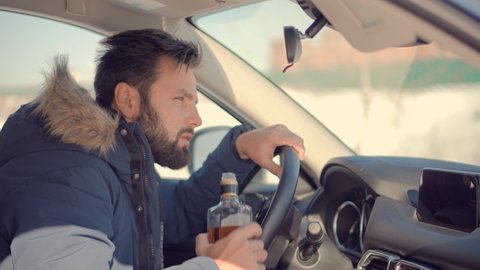 Drunken Driving Risk Car Accident.Man Holding Alcohol Bottle In Car. Dangerous On Road Drunk Driving.Stress Unlawful Intoxicated Drive Auto.Drunk Driving Sitting On Car.Tired Man Illegal Vehicle Drive