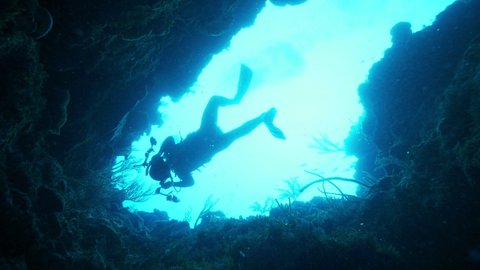 Slow Motion: Scuba Diver Exploring Cave In Sea