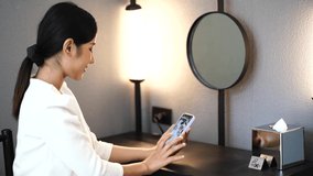 An Asian woman uses a smartphone to play social media and video conferences with friends during the quarantine period in the hotel. 