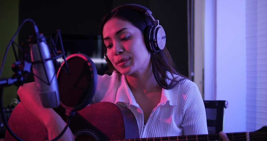 Female singer playing acoustic guitar and singing a song. Asian woman performing vocal artist singing in recording studio. Recording for her album. | Shutterstock HD Video #1068657719