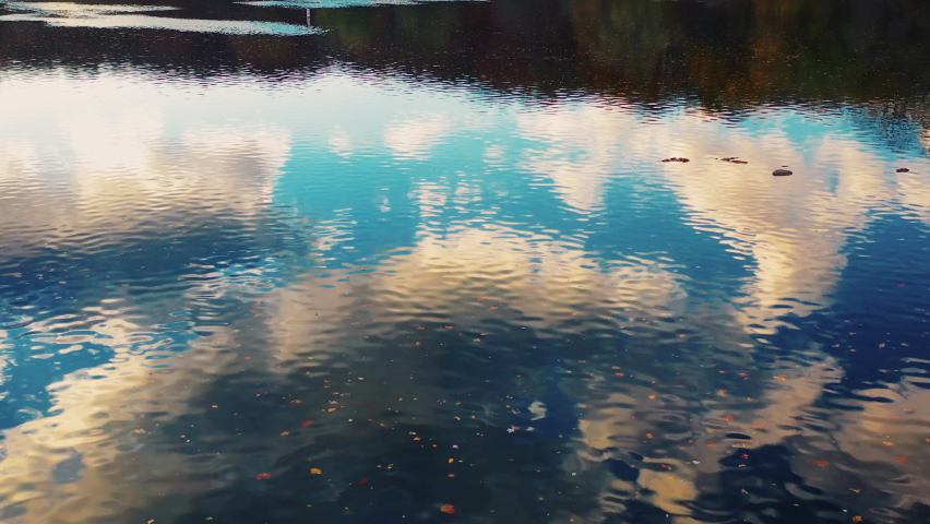 A drone views the beautiful evening golden hour sky through the reflection of the water as it speeds along downstream.