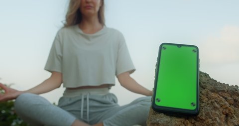 Mock Up Smartphone display green screen preview with girl meditate on background