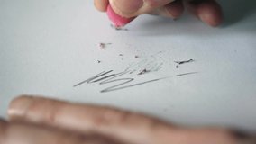 Erasing pencil scribbles - graphite particles from a clean white paper sheet with a rubber while holding sketch with an arm - Powered by Shutterstock - Get 15% off with code: PIKWIZARD15