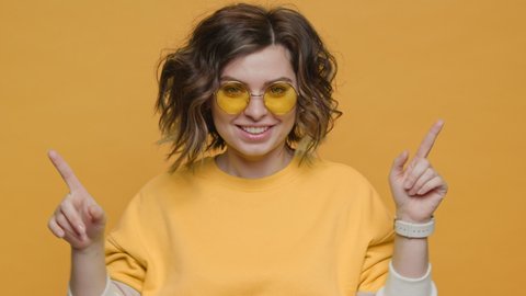Portrait Happy Woman Smiling Dancing to Music Rhythmically to Beat Moving her Hands in Yellow Sweater Yellow Background Slow Motion in Sunglasses . Monotone. Positive Emotions of People. Freedom. Life