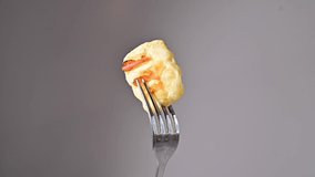 Fork with a slice of fried cheese rolls on a white background.