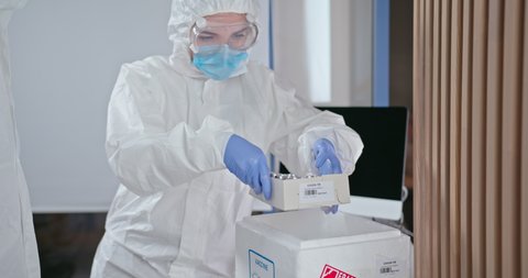 Delivery of the coronavirus vaccine to the vaccination department, the doctor in a protective suit transports doses of the modern vaccine in a heat box with a refrigerant.