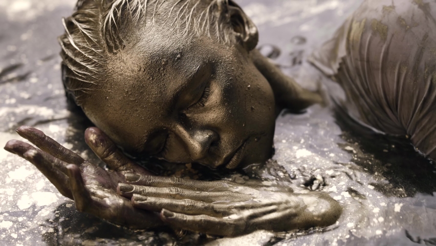 golden woman is lying in water with shiny gold dye, closeup of face, artistic shot and body-art performance Royalty-Free Stock Footage #1068670316