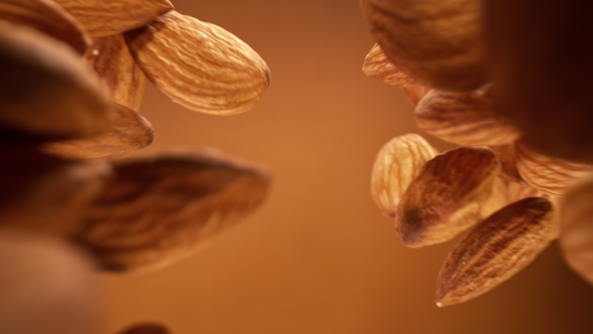 Super Slow Motion Detail Shot of Almonds Falling Down on Brown Background at 1000 fps. | Shutterstock HD Video #1068679013