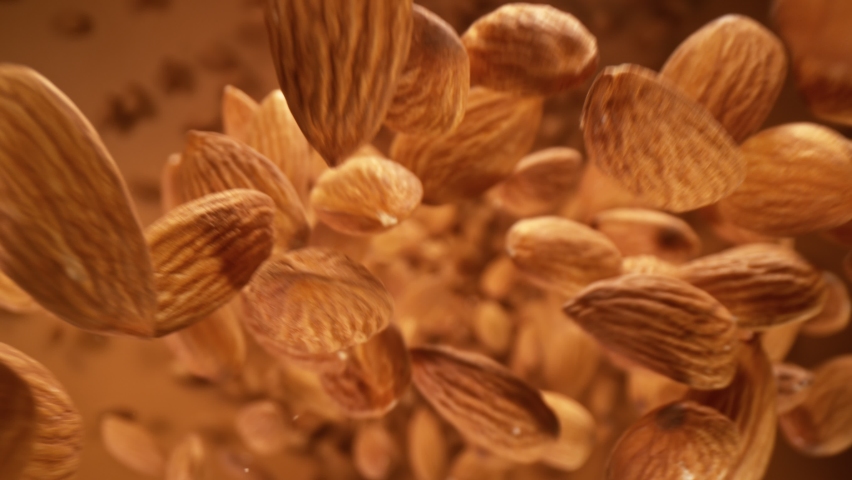 Super Slow Motion Detail Shot of Almonds Falling Down on Brown Background at 1000 fps. | Shutterstock HD Video #1068679013