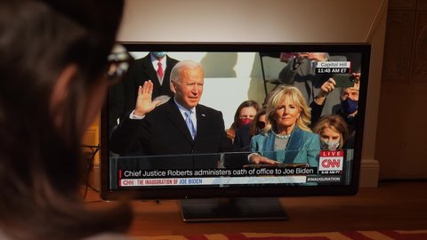 Paris, France - Jan 21, 2021: Happy Couple happy watching TV breaking news of Presidential Inauguration ceremony of Joe Biden the 45th President of United States of America 