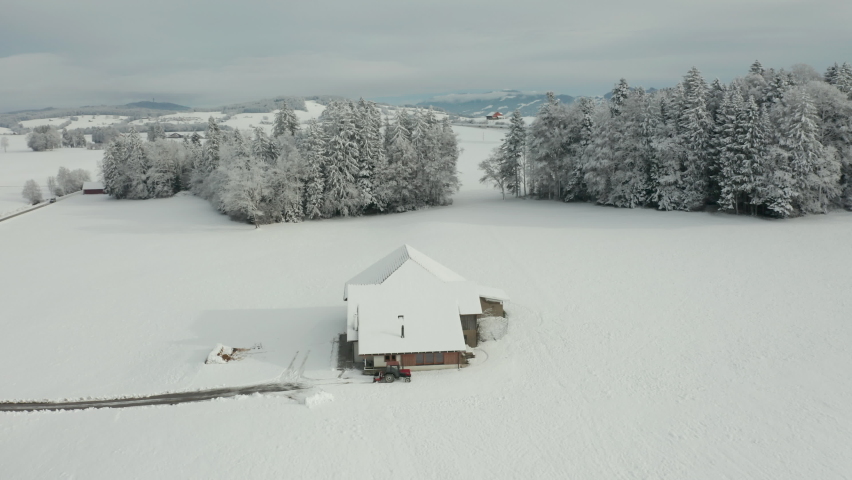 Jib up of small farmhouse standing in snow covered landscape