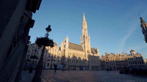Grand Place Brussels, Belgium, wide dolly truck shot sideways with town hall in the center. On a calm warm summer morning with clear blue skies during sunrise.