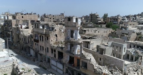 Aerial view with a drone over buildings of Aleppo in Syria 10 years after the civil war. We can see grass covering ruins of building, destroyed after bombing 4K