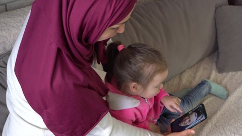 Stay home Ramadan. Online congratulations on the Eid al-Adha holiday in the conditions of Covid - 19 quarantine lockdown and social distance. Muslim mother and child talking on video call with man