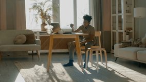 WIDE African American Black kid boy doing his homework or having a video call with class and teacher. Distance learning from home during isolation. Shot with 2x anamorphic lens