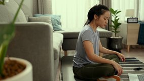 Asian woman is pushing a dumbbell and doing video exercises in laptop in living room at home.Exercise,Work out,Fitness and lifestyle sport healthy concept.