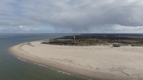 4k aerial video of the dutch island of Texel with sand beach, dunes and red light house on a sunny day with white clouds