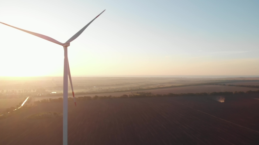 Wind turbines power plant aerial sunset view green energy. Wind mills rotating generating renewable energy at golden hour light flares. Cinematic rural green energy 4K | Shutterstock HD Video #1068695807