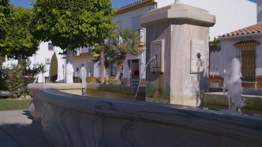 Water fountain in a town square surrounded by trees