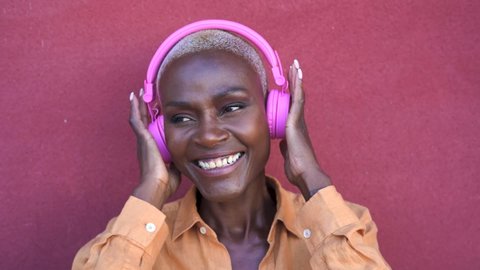 Happy senior Afro woman having fun listening music with wireless headphones