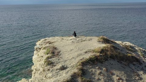 Pensive boy admires the horizon of the sea on a large rock
Scenographic shooting with drone, panoramic around the subject.