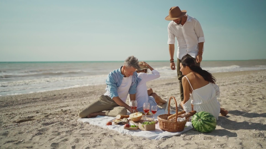slow motion lovely two couples at picnic - happy friends having breakfast at summer beach party or picnic. lovely couples having fun at sea vacation travel and kissing Royalty-Free Stock Footage #1068708584