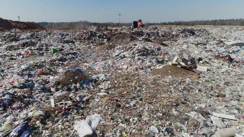 Open city garbage dump. Birds are flying, a bulldozer is leveling piles of waste, aerial photography. Concept: environmental problems of the city, environmental pollution, landfill for waste disposal.