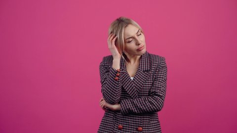 The mature woman who meditates on new possibilities, new ideas, new concepts of achievement, finally smiles fulfilled. Beautiful young mature blonde in pink jacket. Isolated on a pink background