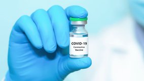 A doctor in blue gloves holding a bottle with coronavirus vaccine.The concept of medicine, healthcare and science. Video, full hd,