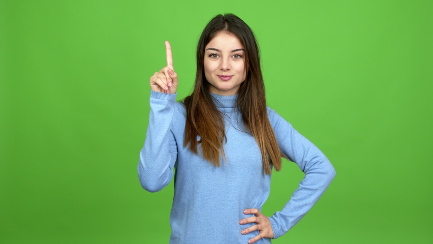 Young caucasian woman showing and lifting a finger in sign of the best over isolated background. Green screen chroma key